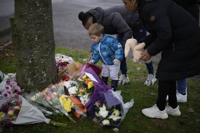 Flowers are left near the scene after three young boys died when a number of children fell through ice on a lake in Solihull. 
