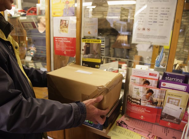 <p>Customers weigh packages at the post office.</p>