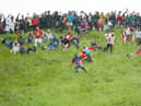 Contestants in the men’s downhill race chase the cheese down the hill in June 2022 in Gloucester, England. 