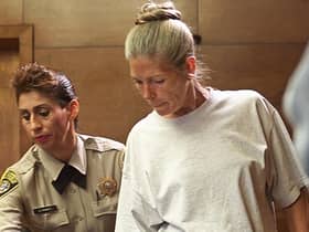 Corrections officer Sandra Fuentes (L) assists inmate Leslie Van Houten (R) as arrives for her parole hearing before members of the Board of Prison Terms 28 June 2002 at the California Institution for Women in Corona, California.