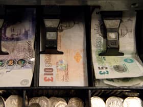An open cash register containing pound coins and notes is pictured in a convenience store in London