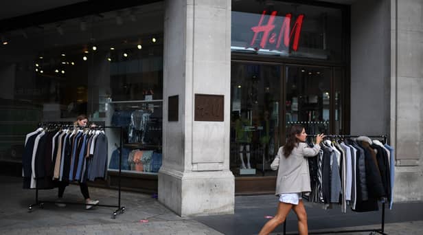 Retail workers move rails of clothes past a H&M store on Oxford Street.