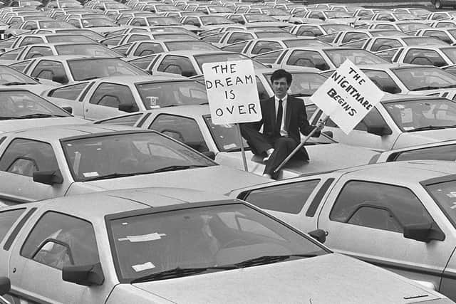Final day of De Lorean in May 1982. One worker pictured amongst a sea of cars in the compound of the plant holding two placards. The first reads 'The Dream Is Over' the second says 'The Nightmare Begins'. Picture: Pacemaker Press