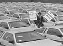 Final day of De Lorean in May 1982. One worker pictured amongst a sea of cars in the compound of the plant holding two placards. The first reads 'The Dream Is Over' the second says 'The Nightmare Begins'. Picture: Pacemaker Press
