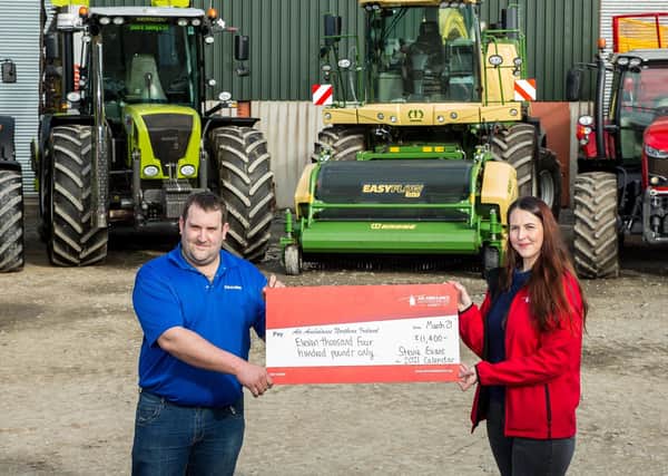 Steven Evans presents Grace Williams, NI Air Ambulance Area Fundraising Manager with a cheque for £11,400 in front of some of the machinery that features in his calendar.