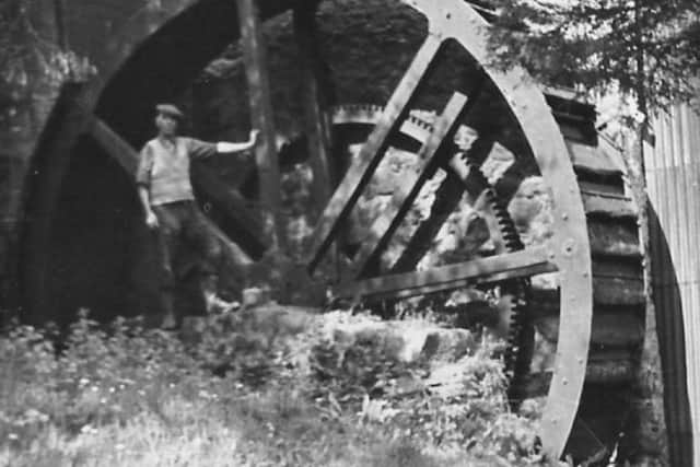Daniel Dan Donnelly stands beside the wheel of his scutching mill