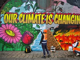 Artists paint a mural on a a wall next to where the COP26 UN Climate Summit will take place in November.