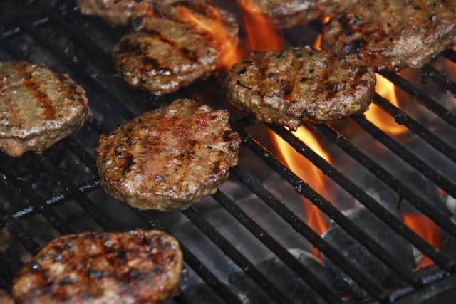 Hamburgers cooking on barbeque grill with flames