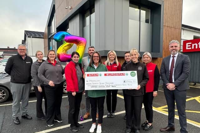 Store managers from the 10-store fundraising initiative presenting the cheque to Joanne Young from Macmillan Cancer Support