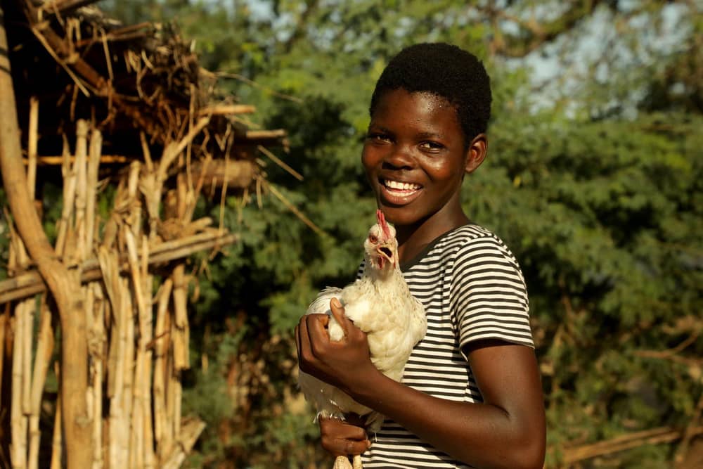 Young farmer Sarah (16) and one of the chickens her family received with support from Concern Worldwide in Malawi.