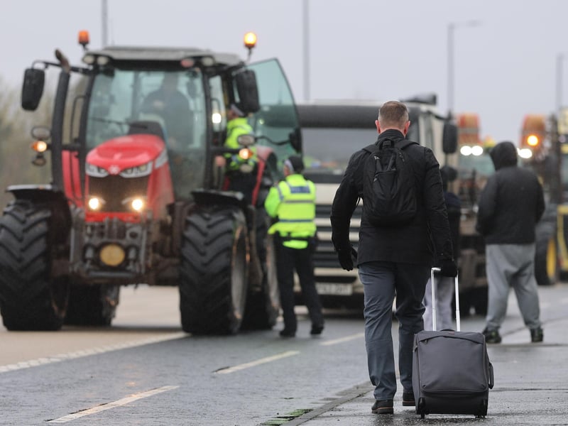 A person with their luggage walks past vehicles on Sydenham by-pass in Belfast, as the National Fuel Protest against rising fuel prices continues. Picture date: Tuesday April 14, 2026. PA Photo. Photo credit should read: Liam McBurney/PA Wire