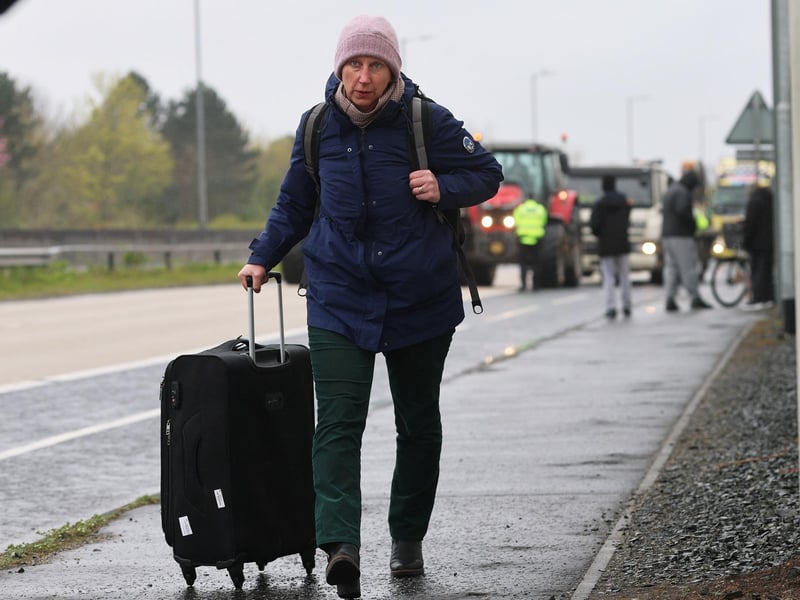 A person with their luggage walking on Sydenham by-pass in Belfast towards Belfast Airport, as the National Fuel Protest against rising fuel prices continues to cause delays. Picture date: Tuesday April 14, 2026. PA Photo. Photo credit should read: Liam McBurney/PA Wire