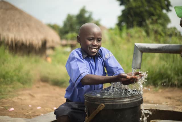 A Uganda boy enjoying fresh water from the new Fields of Life dug well in his village.