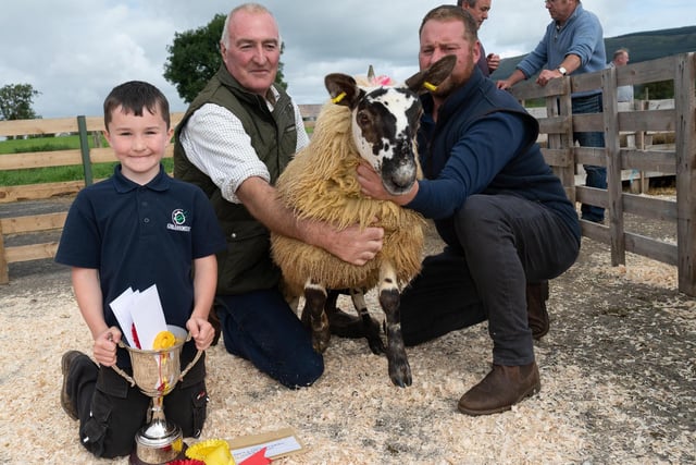 Arnold Douglas and Sam Douglas  with the champion grey face and Alwyn McFarland, judge, at the Alexander Gourley open air sheep show and sale at Aghanloo on Tuesday morning. Photo Clive Wasson