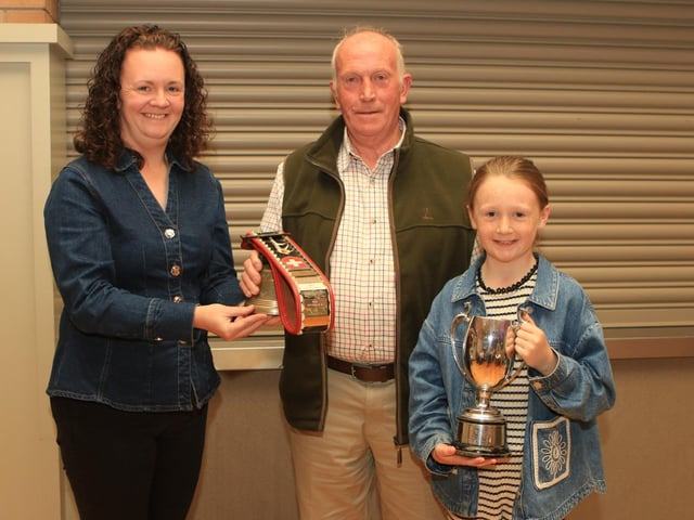 Geraldine McElduff (Countryside Services) with her daughter Molly presented the Perpetual cow bell winner, Bangor Six Road Ends Farmers' Union Perpetual trophy to Joe Wilson for the Champion Simmental Female at Balmoral Show 2026 (Ballinalare Farm Nikita)