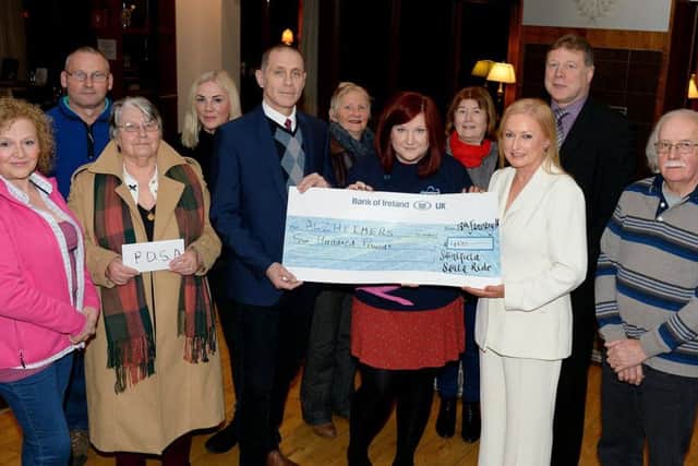 Joan Cunningham, organiser of Saintfield Christmas Charity Ride, and Alastair McIlveen, North Down Marquees, present cheques to Alzheimer's Society Community Fundraiser Laura Summerbell and PDSA Fundraiser Valerie Morrison . Also pictured are Lorraine Johnston, Maurice Hanna, Angela Cartright, Winifred Clinghan, Jean O'Goan, John Barclay (Manager Bank of Ireland, Downpatrick) and Robin Patterson.