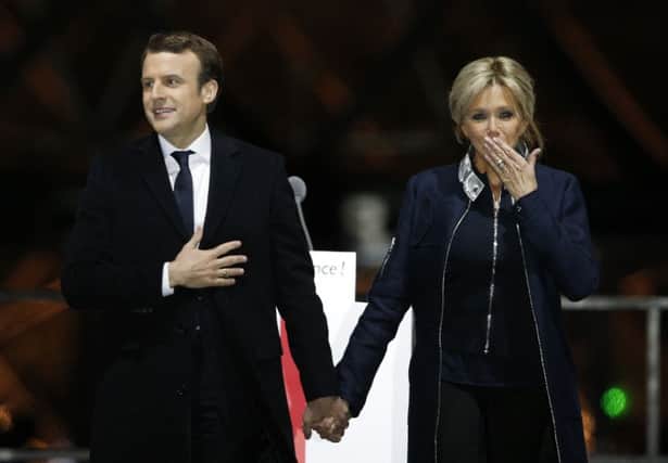 French President-elect Emmanuel Macron holds hands with his wife Brigitte during a victory celebration outside the Louvre museum in Paris, France, Sunday, May 7, 2017. Speaking to thousands of supporters from the Louvre Museum's courtyard, Macron said that France is facing an "immense task" to rebuild European unity, fix the economy and ensure security against extremist threats. (AP Photo/Thibault Camus)