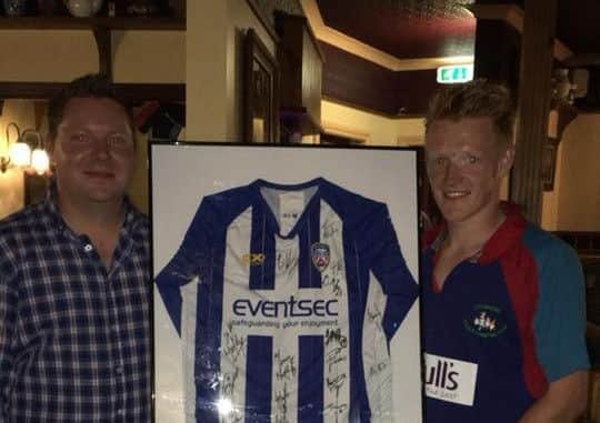 Club secretary Ryan Adams passing over the signed shirt from the auction to Stuart Mills