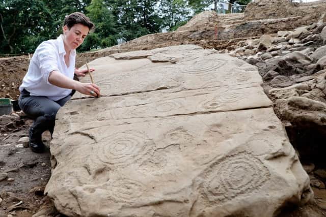 Dr ClÃ­odhna NÃ­ LionÃ¡in, Devenish's lead archaeologist is pictured with some of the pieces of unearthed Kerbstone from the recently discovered Megalithic passage tomb within the BrÃº na BÃ³inne World Heritage Site