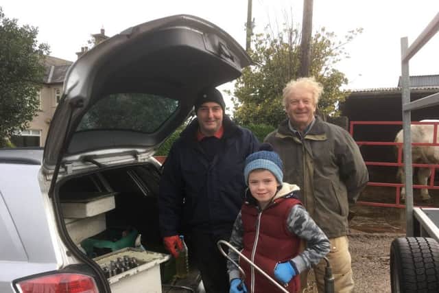 Freeze brander Richard Gillespie, left, and son Alan, holding the Easy Boss E,  with visiting vet Dr Don Finlay. One of the first in NI to use this oral distraction device on a daily basis Richard finds it an essential tool for calming cattle.