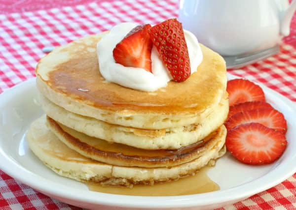 Fresh and homemade pancakes topped with cream and strawberries.