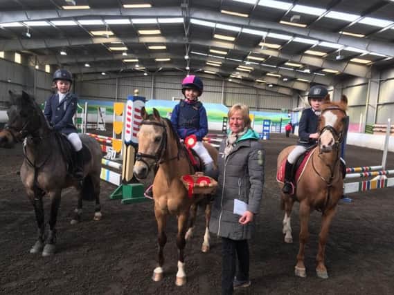 A trio of competitors are presented with their rosettes