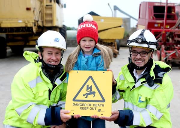Caitlin Spence helps Safety Engineers Hal Steele and Mark Moore from NIE Networks send a safety message to the farming community this winter.