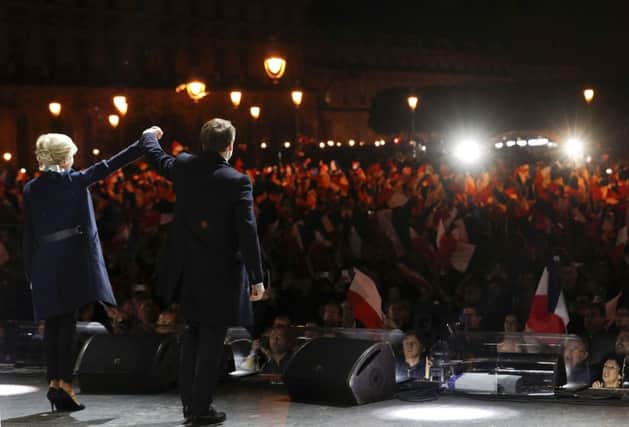 French President-elect Emmanuel Macron and his wife stand on the stage at his victory rally near the Louvre museum, Sunday May 7, 2017 in Paris. Speaking to thousands of supporters from the Louvre Museum's courtyard, Macron said that France is facing an "immense task" to rebuild European unity, fix the economy and ensure security against extremist threats. (Philippe Wojazer, Pool via AP)